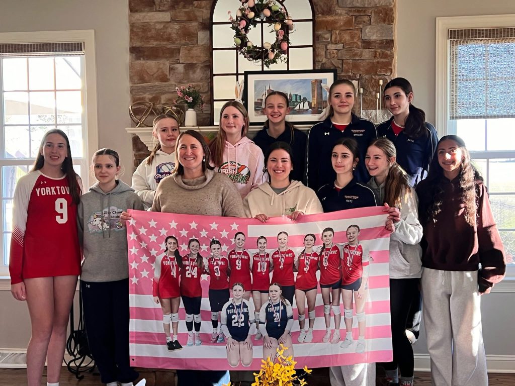 Yorktowne girls volleyball athletes and families with a team poster
